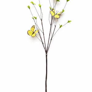 May include: A decorative floral stem featuring yellow butterflies and small green leaves. The butterflies have black markings on their wings. The stem is brown and the background is white.