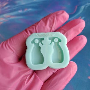 May include: A light blue silicone mold with two spray bottle shapes. The mold is labeled "Moldeden".