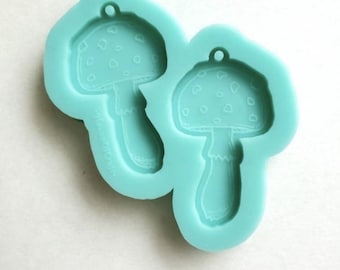 May include: A teal silicone mold with two mushroom shapes. The mushrooms have white spots and a hole at the top for hanging.