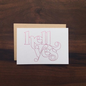 May include: A white card with the words "hello yes" written in pink cursive.