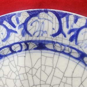 May include: A white ceramic plate with a blue and white floral design. The plate has a crackled glaze, giving it a rustic look.