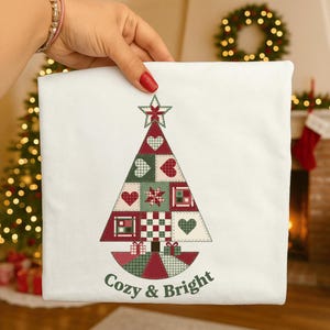 May include: White Christmas-themed decorative pillow with a patchwork Christmas tree design. The tree features red, green, and white squares, hearts, and a star. The words "Cozy & Bright" are printed at the bottom.