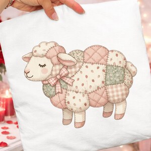May include: White cushion featuring a charming sheep design. The sheep is crafted from patchwork in pink, green, and cream hues, adorned with strawberry and floral motifs. It has a pink bow and a gentle expression.