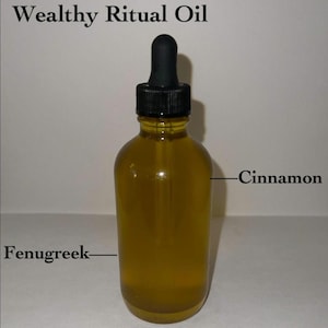 Könnte beinhalten: Eine klare Glastropfflasche gefüllt mit goldgelber Flüssigkeit. Der Text Wealthy Ritual Oil steht über der Flasche, mit Linien, die auf die Flüssigkeit zeigen, beschriftet mit Cinnamon rechts und Fenugreek links. Sie hat einen schwarzen Verschluss.