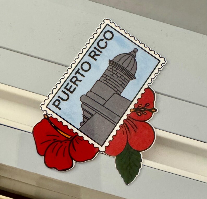 May include: A sticker featuring a gray lighthouse illustration on a blue background, labeled "PUERTO RICO" in white text. The sticker is adorned with a red hibiscus flower and green leaf.