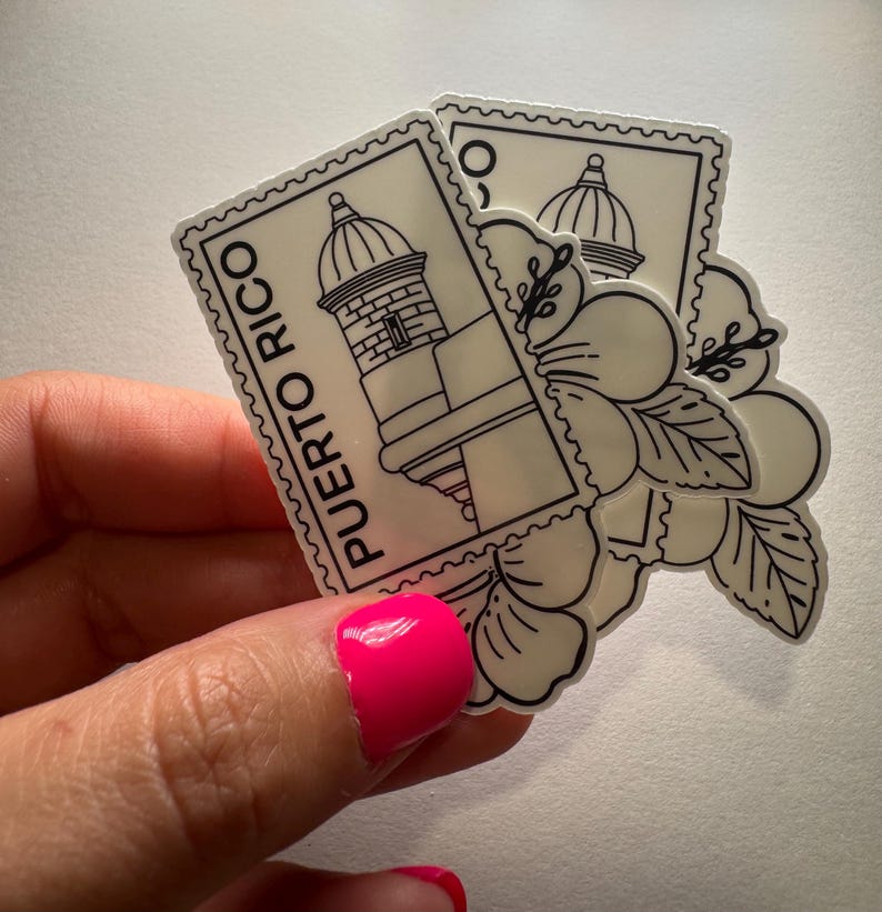 May include: Two stickers featuring a black and white design of a Puerto Rican landmark and a flower. The stickers are in the shape of postage stamps, with the words "Puerto Rico" printed vertically on one. The stickers are held in a hand.