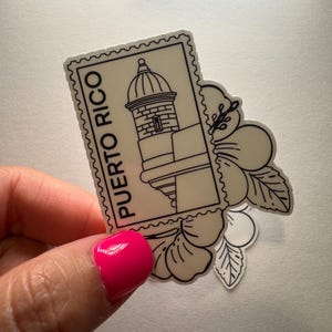 May include: A sticker featuring a black and white illustration of a Puerto Rican landmark, resembling a postage stamp. The stamp is accompanied by a floral design. The words "PUERTO RICO" are printed on the stamp.
