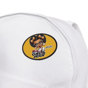 May include: A white backpack with a yellow oval patch featuring a cartoon girl with glasses and books. The patch says "Cute & Nerdy" and "You Did Excellent".