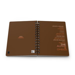 May include: A brown spiral bound notebook with the words "The Alpha & Omega" in a gradient of orange, red, and brown. The notebook also includes a list of names for God in Hebrew and English.