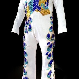 Da Neena Tailor confeccionó el traje de capa con cinturón de pavo real del rey.