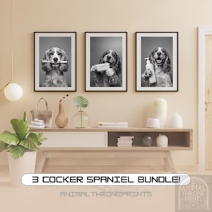 Puede incluir: Un conjunto de tres fotos en blanco y negro con un Cocker Spaniel en diferentes poses. El perro sostiene un cepillo de dientes, una pastilla de jabón y una botella de jabón. Las fotos están enmarcadas en marcos negros y están colgadas en una pared.