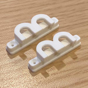 May include: Two white plastic cable organizers with three cable slots each. The organizers are designed to hold cables neatly and securely.