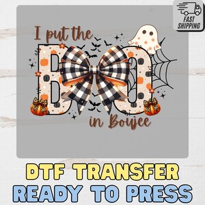 May include: A Halloween-themed graphic with the phrase "I put the BOO in Boujee." The design features a large black and white plaid bow, pumpkins, bats, and a ghost. The words "DTF TRANSFER READY TO PRESS" are at the bottom.