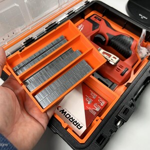May include: A black and orange hard case with a red and black electric nail gun and three orange trays of nails. The trays are labeled "ARROW".