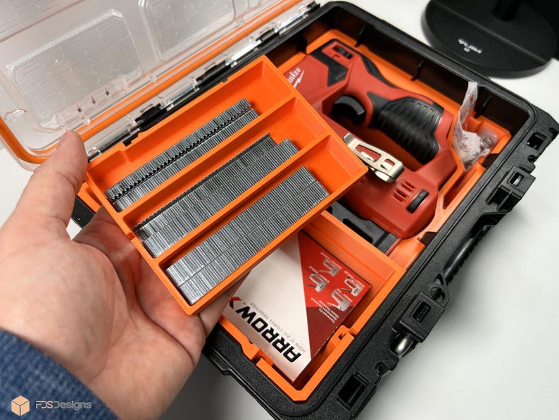 May include: A black and orange hard case with a red and black electric nail gun and three orange trays of nails. The trays are labeled "ARROW".