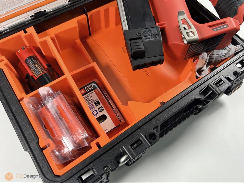 May include: A black and orange hard case with a red and black power tool inside. The case has a foam insert with compartments for the tool and accessories. The tool has a black handle and a red body. The case has a label that says "PORTER CABLE".