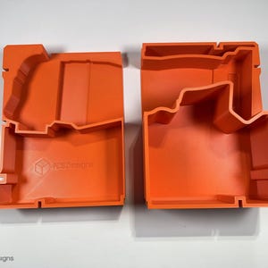 May include: Two orange plastic storage boxes with custom cutouts for holding tools. The boxes are open and show the interior cutouts. The box on the left has the text "F&S Designs" printed on the bottom.