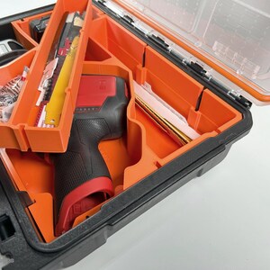 May include: An orange and black tool case with a red and black power tool inside. The case has multiple compartments for organizing tools.