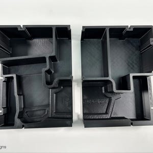 以下が含まれることがあります： 複数の仕切りが付いた黒いプラスチック製の収納容器2つ。工具や電子機器などの小さなアイテムを収納するために設計されています。