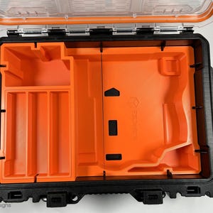 May include: An open black and orange hard plastic case with a removable foam insert. The foam insert has multiple compartments for organizing tools and other small items.
