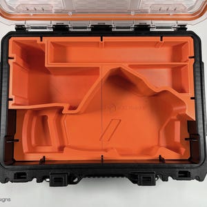 May include: An open black and orange tool case with a custom foam insert. The foam insert has a cutout for a tool, and the case has a clear plastic lid.