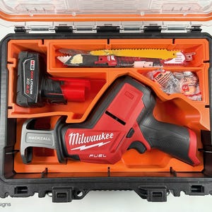 May include: A red and black Milwaukee FUEL reciprocating saw with a black and gray Hackzall blade, a red M12 REDLITHIUM XC 4.0 battery, and a variety of saw blades in a black and orange hard case.