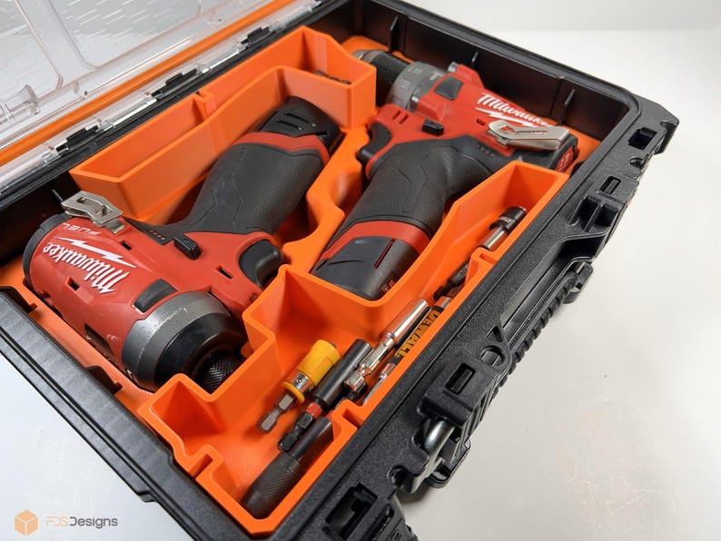 May include: A black and orange tool case with two red and black cordless drills and various bits inside. The drills are labeled "Milwaukee".