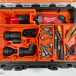 Puede incluir: Una caja de herramientas naranja y negra con un taladro Milwaukee FUEL y varios brocas y accesorios. La caja tiene varios compartimentos para organizar las herramientas.