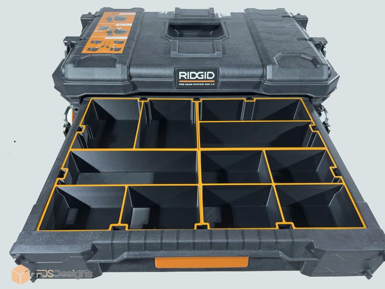 May include: A black and orange RIDGID Pro Gear System 2.0 tool storage box with a pull-out drawer. The drawer is divided into multiple compartments with yellow dividers. The box has a handle and the brand name is visible.