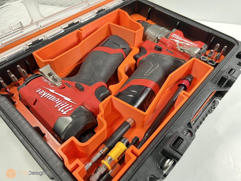 May include: An open black and orange tool case containing red and black power tools. The case holds two red and black Milwaukee FUEL drills, drill bits, and other tools. The tools are neatly arranged within the case.