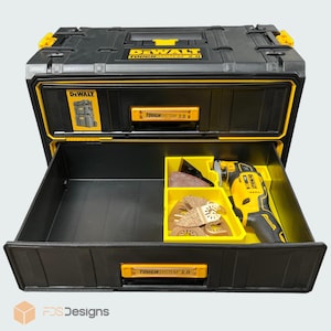 May include: A black and yellow DeWalt ToughSystem 2.0 tool storage unit with an open drawer. The drawer contains a yellow and black oscillating multi-tool and several metal sanding attachments organised in a yellow plastic insert tray.