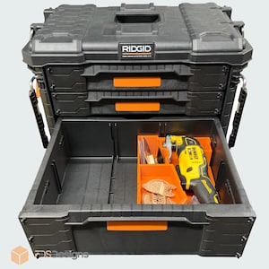 May include: Black RIDGID Pro Gear System 2.0 tool storage box with orange detailing. The open bottom drawer reveals an orange organiser with a yellow and black DEWALT oscillating multi-tool and small items.