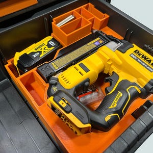 Peut inclure: Un cloueur sans fil DeWalt 20V sans balai jaune et noir et une batterie sont rang&eacute;s dans un organisateur orange &agrave; l'int&eacute;rieur d'une bo&icirc;te &agrave; outils noire. La bo&icirc;te &agrave; outils comporte des compartiments de rangement orange suppl&eacute;mentaires.