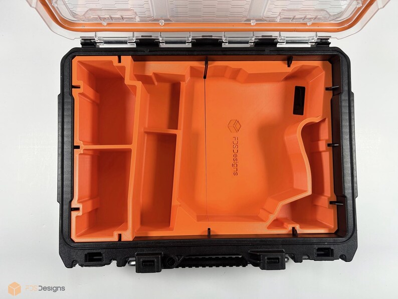 May include: An open black and orange tool case with a foam insert. The insert has multiple compartments and a large cutout for a tool. The case has a clear lid and the text "SCSSSC" is printed on the foam insert.