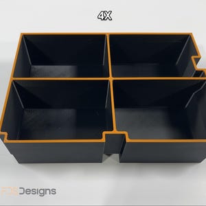 May include: A black and orange organizer with four compartments. The organizer has a rectangular shape with a cutout on one side. The text "4X" is visible at the top.