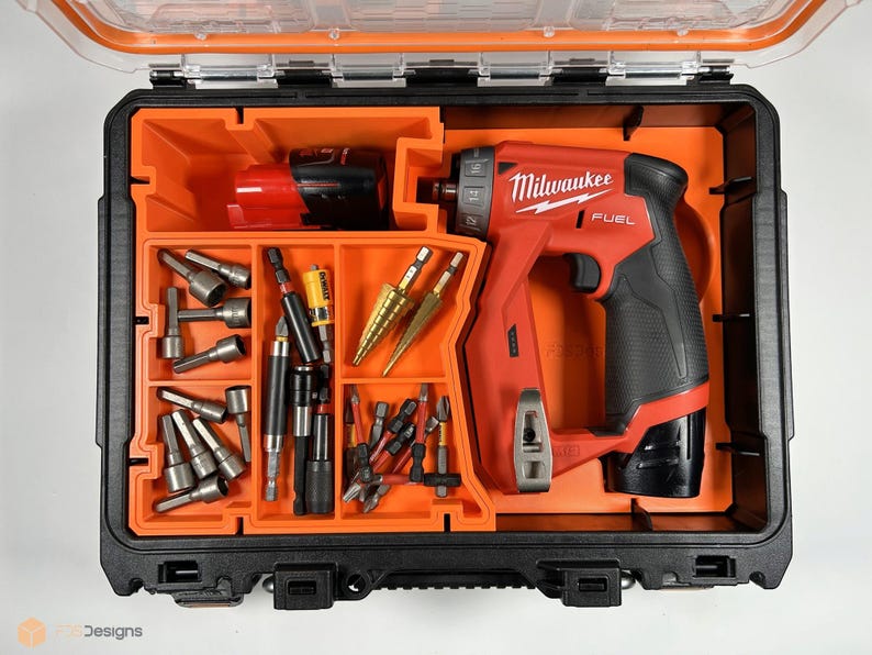 Puede incluir: Una caja de herramientas naranja y negra con un taladro Milwaukee FUEL rojo y negro y varios brocas y accesorios.