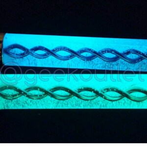 Puede incluir: Dos tubos de vidrio que brillan en la oscuridad con una tapa de metal plateado en cada extremo. Los tubos contienen un l&iacute;quido azul y verde que gira.