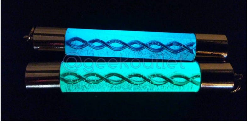 Puede incluir: Dos tubos de vidrio que brillan en la oscuridad con una tapa de metal plateado en cada extremo. Los tubos contienen un l&iacute;quido azul y verde que gira.