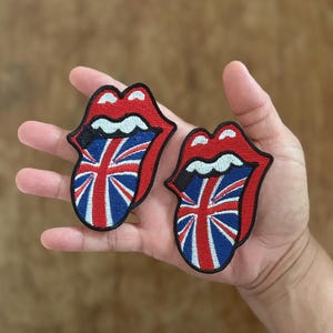 Puede incluir: Dos parches bordados de color rojo, blanco y azul de una lengua que sobresale con el diseño de la bandera de la Union Jack.