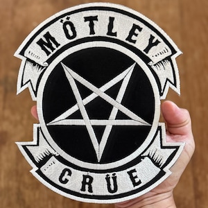 以下が含まれることがあります： 五芒星と円の中に「MÖTLEY CRÜE」という文字が書かれた、黒と白の刺繍パッチです。