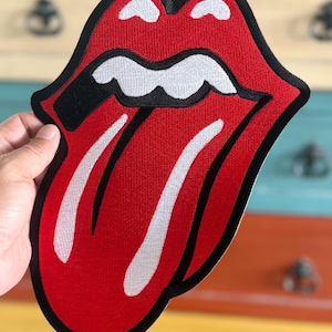 May include: Red and white embroidered patch of a tongue sticking out with a black outline. The tongue has two white stripes down the middle.