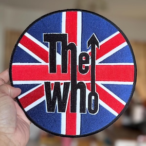 May include: A round, embroidered patch featuring a Union Jack flag design and the words "The Who" in black lettering.