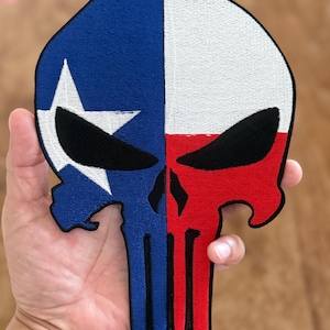 Op de afbeelding: Een geborduurde patch met de vlag van de staat Texas en een schedel met een Punisher-logo, in rood, wit en blauw.