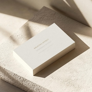 Op de afbeelding: Een witte visitekaartje met de tekst "GOLD FOIL EFFECT", "DEBOSSED EFFECT" en "EMBOSSED EFFECT" gedrukt in goudfolie.
