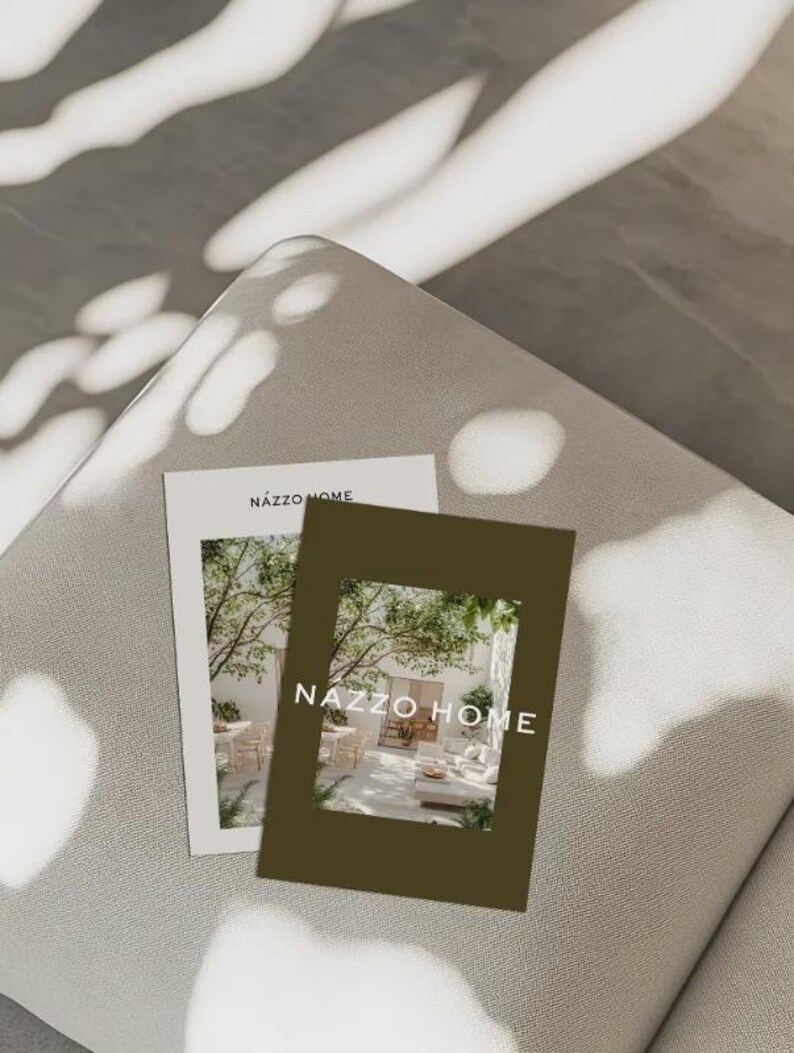 May include: Two brochures with the text "NAZZO HOME" are displayed on a light gray surface. One brochure is white with a photo of an outdoor living space. The other is a dark olive green with a photo of an outdoor living space.