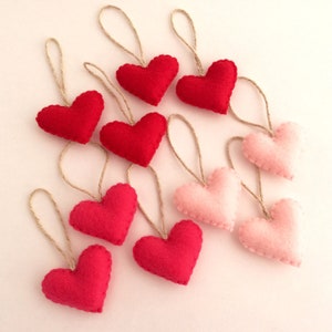 May include: A garland of felt hearts in shades of pink and red, each heart is attached to a twine string.