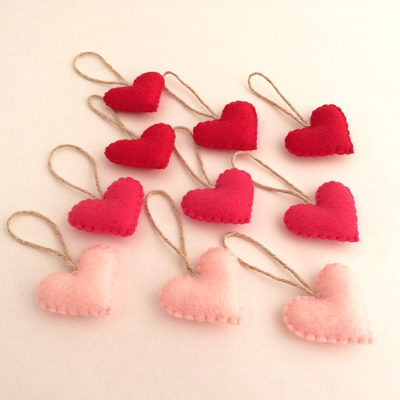 May include: A garland of felt hearts in pink and red, each heart is attached to a twine string.
