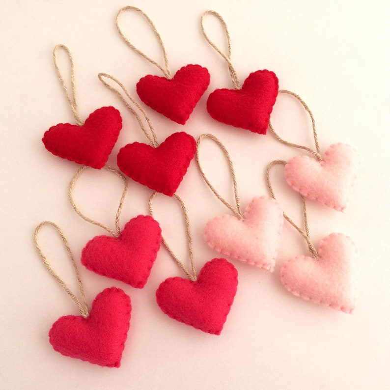May include: A garland of felt hearts in shades of pink and red, each heart is attached to a twine string.