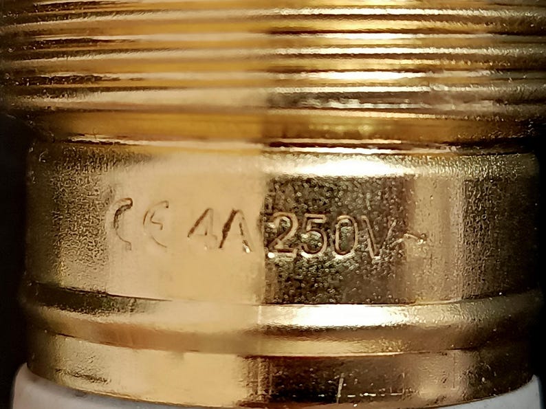 May include: Close-up of a gold-coloured electrical component with the text "CE 4A 250V" printed on it.