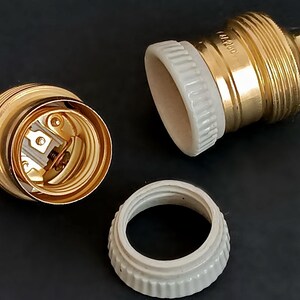 May include: Two gold-coloured light bulb sockets with white ceramic parts. The sockets are disassembled, showing the internal wiring and the ceramic parts.